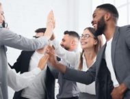 business men and women high fiving in a group