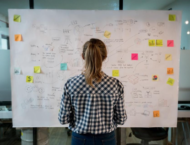 back of woman standing infront of a board full of notes